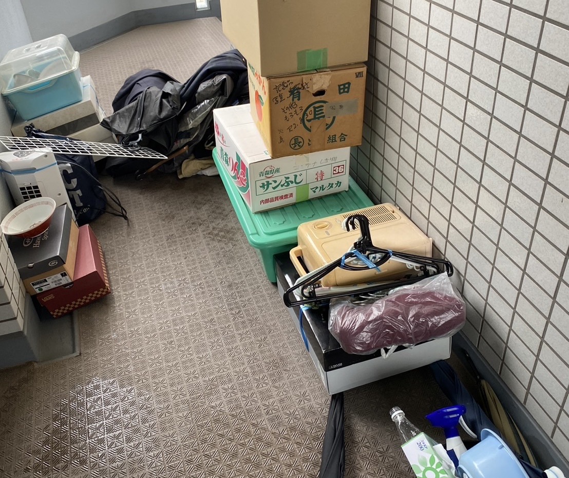 博多区博多駅前での回収前｜共用廊下に並んだ段ボールと生活用品